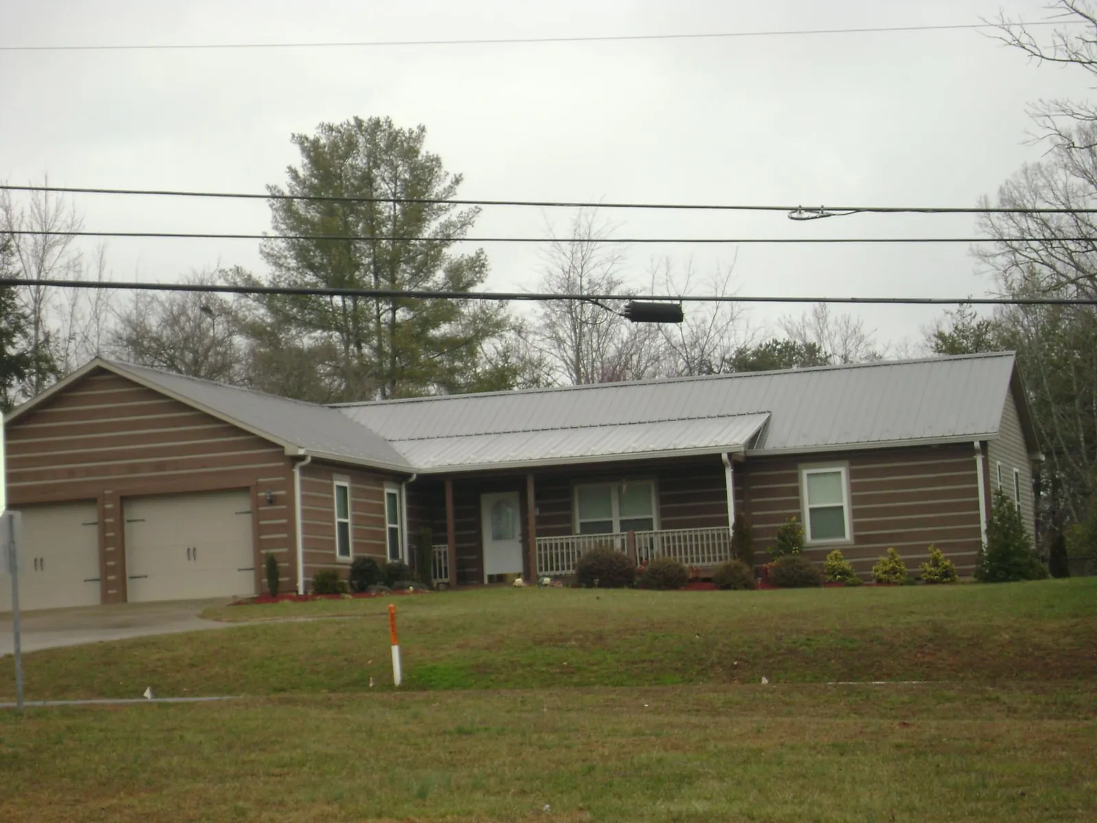 Gray metal roof on a log sided ranch home with a front porch in Aurora